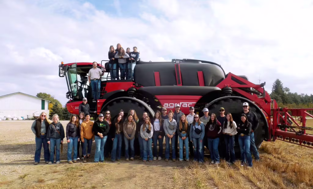 Agros students' group photo in front of sprayer equipment on farm tour